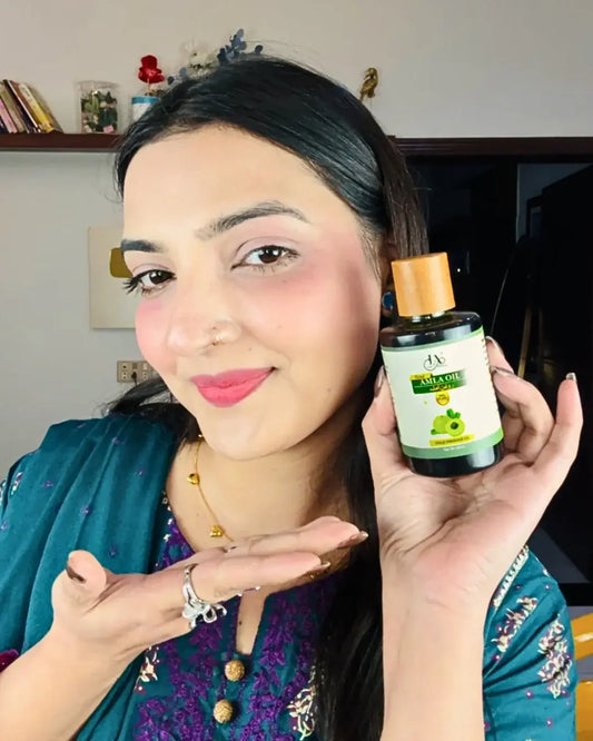 Just Amna amla oil bottle held by model, wooden cap and label visible