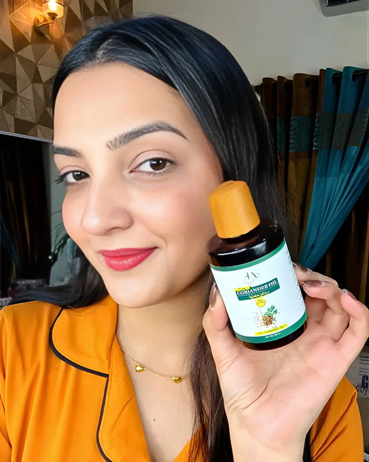 Woman smiling while holding a bottle of Just Amna cold pressed coriander oil.