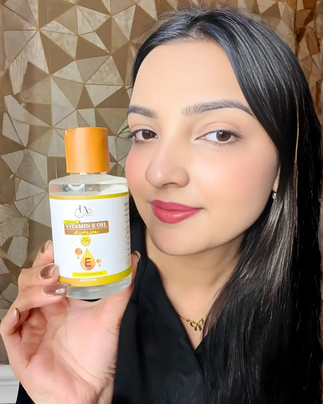Woman showcasing Just Amna pure Vitamin E oil for face and skin glow.