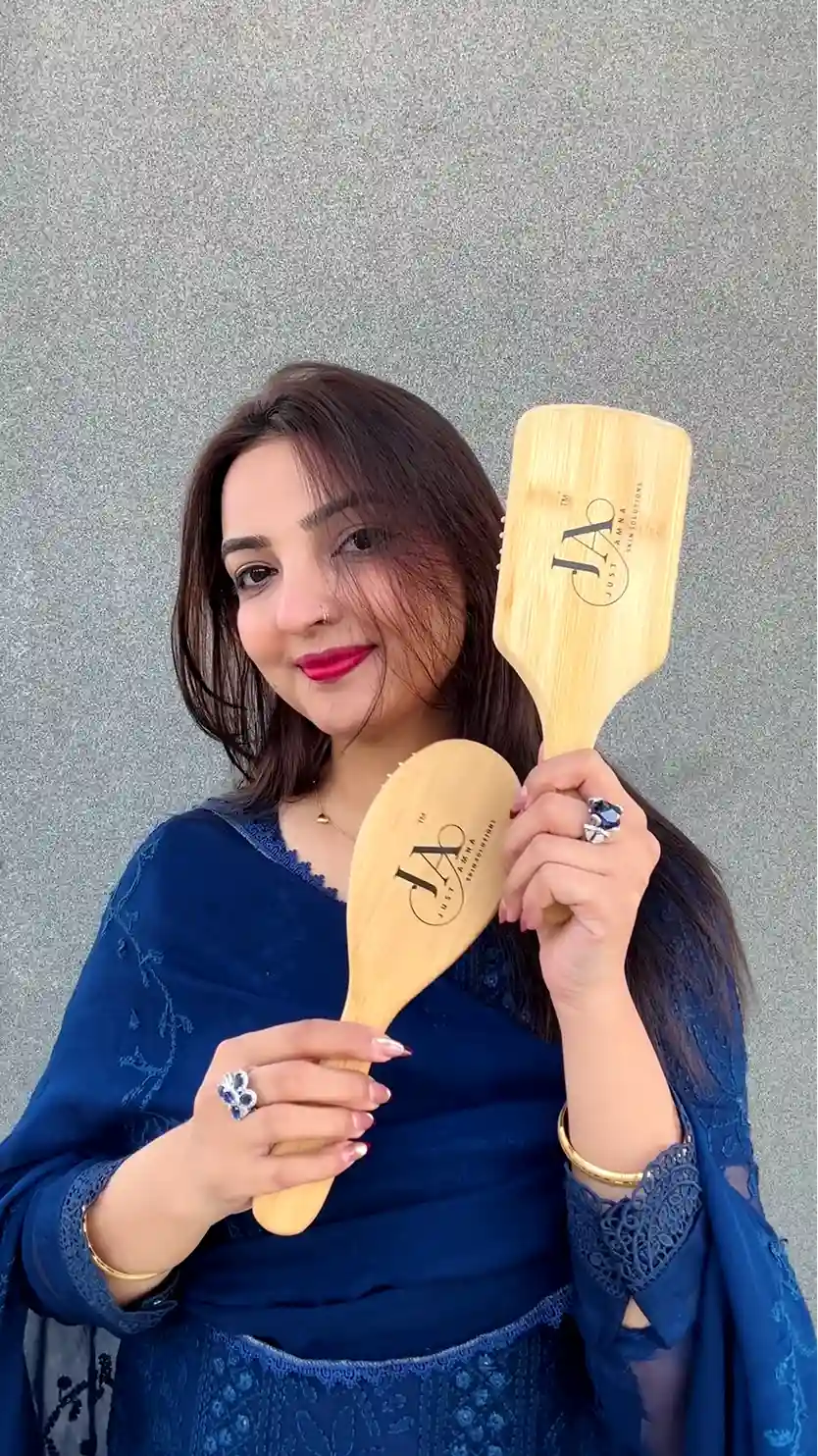 Just Amna two wooden brushes held by model in blue outfit, engraved JA logos visible