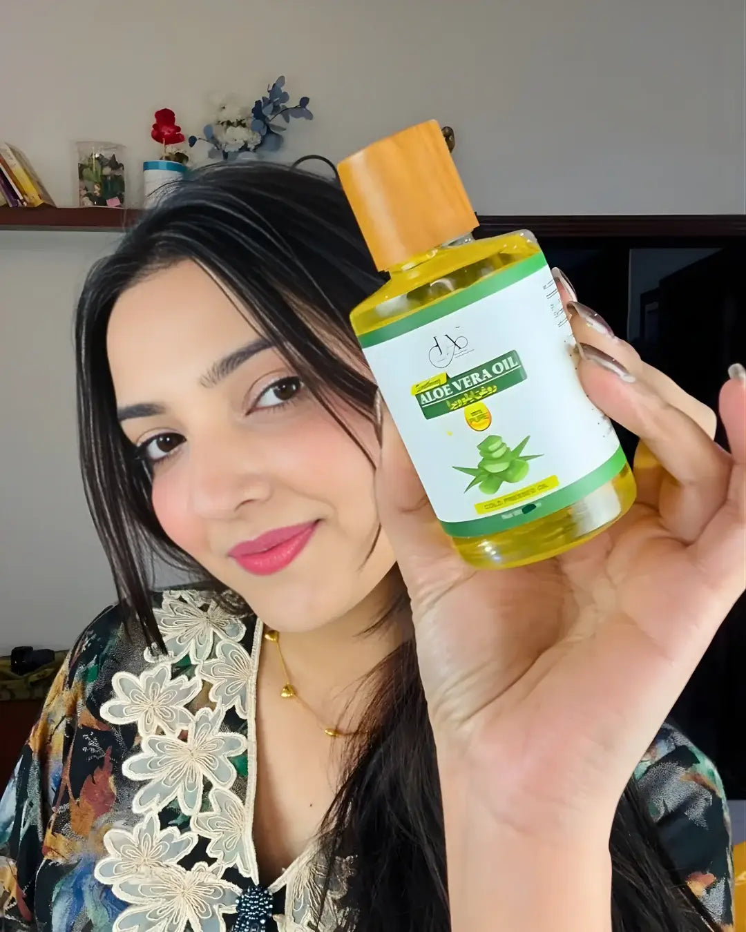 Woman showing Just Amna cold pressed aloe vera oil for natural hair and skin care.