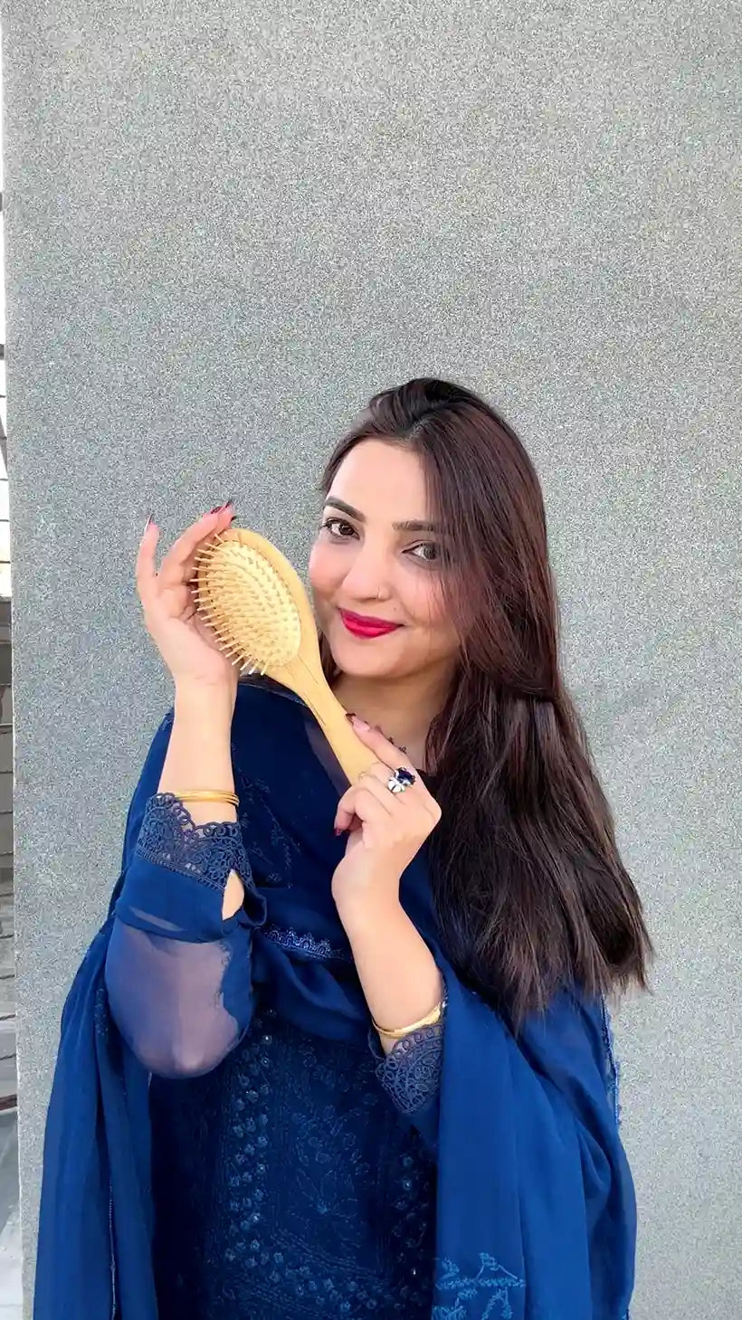 Model holding a Just Amna bamboo hair brush for daily hair care.