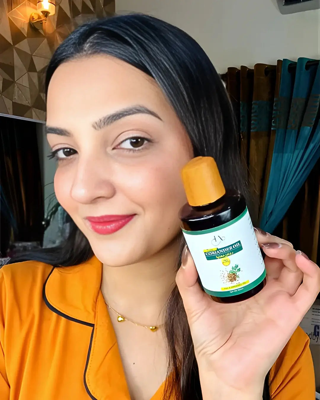 Woman smiling while holding a bottle of Just Amna cold pressed coriander oil.