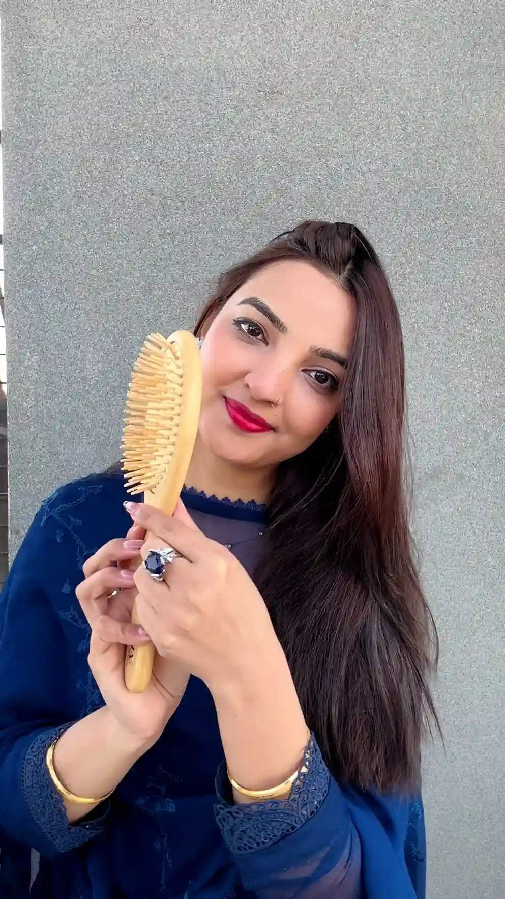 Smiling woman showcasing the Just Amna natural wood hair brush.