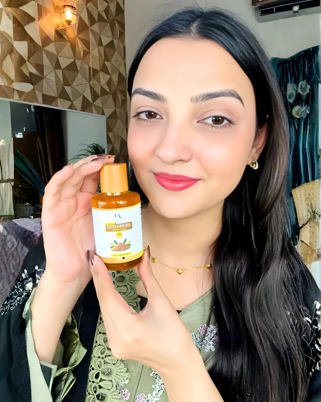 Woman smiling while holding a bottle of Just Amna cold pressed mustard oil for hair care.