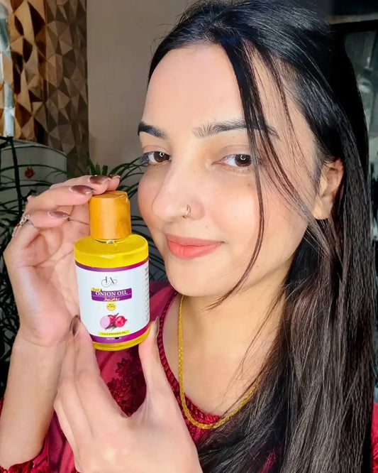 Woman showing Just Amna onion oil bottle for hair growth and scalp care.
