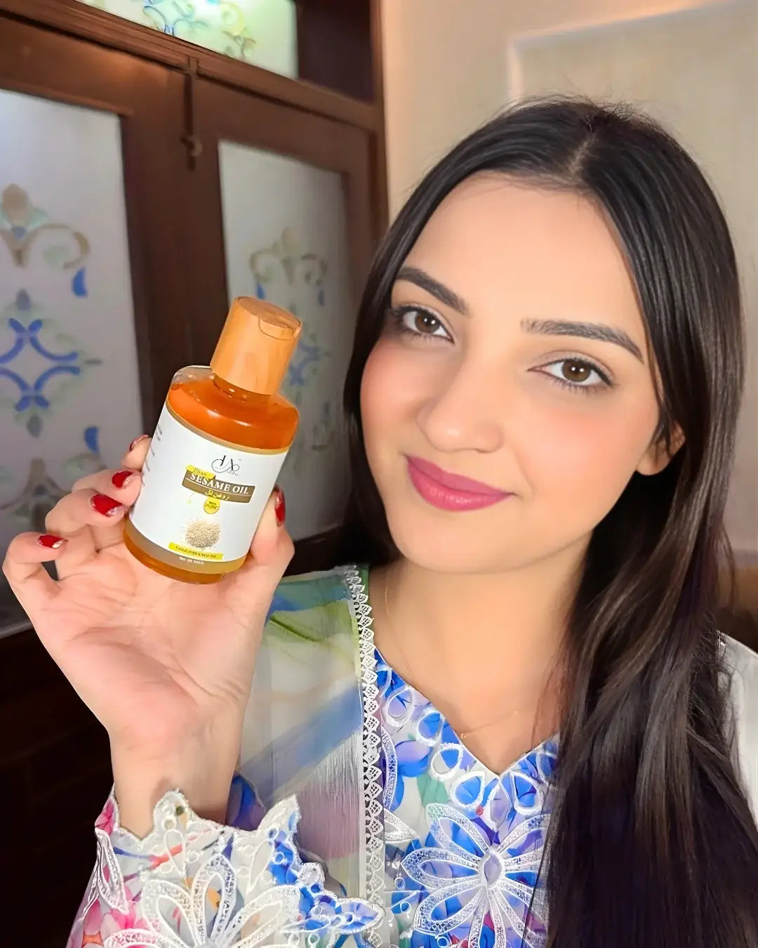 Woman holding Just Amna cold pressed sesame oil bottle for hair and skin.
