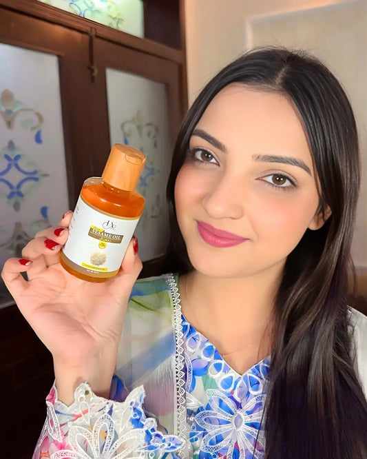 Woman holding Just Amna cold pressed sesame oil bottle for hair and skin.